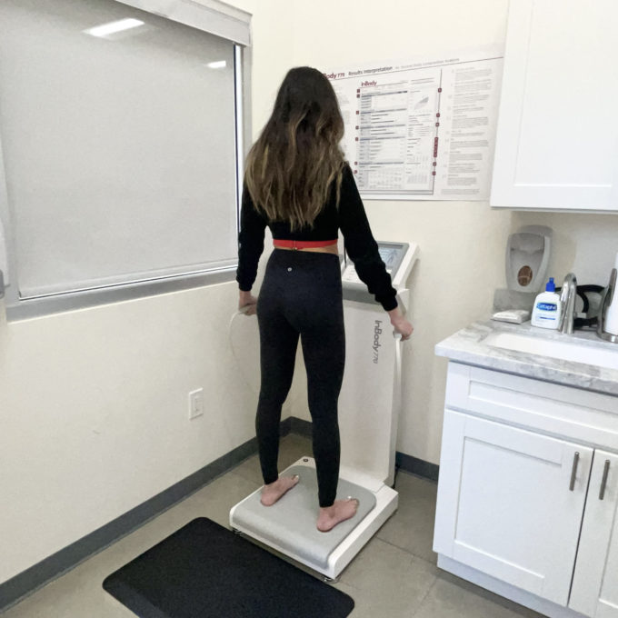 A woman standing on a scale in a medical office.