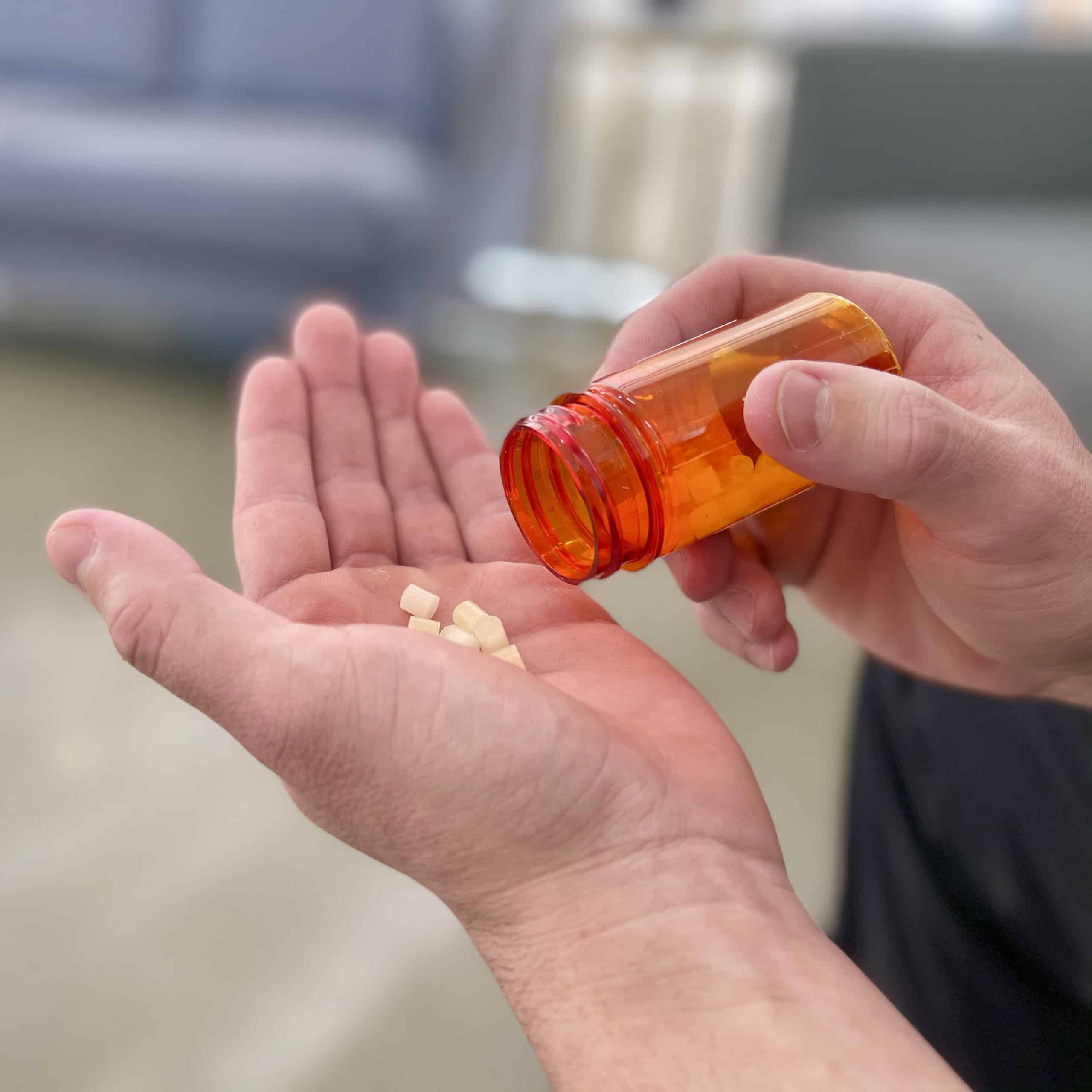 A man is holding a pill bottle in his hand.