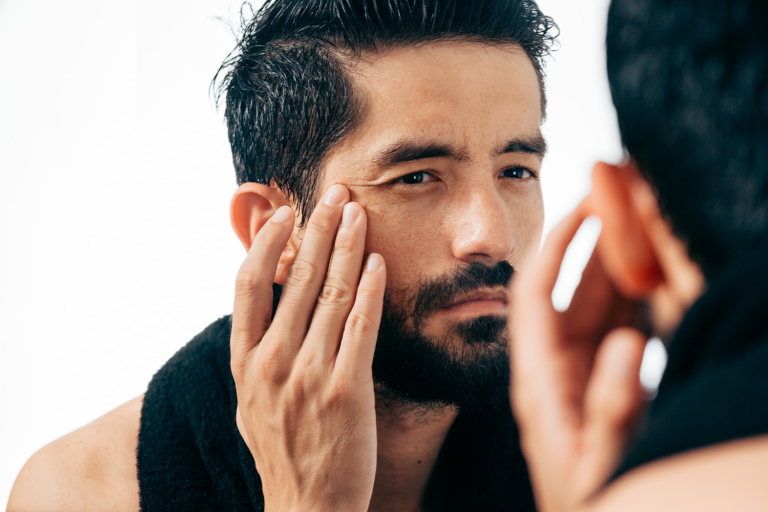 A man with a beard is looking at his face.