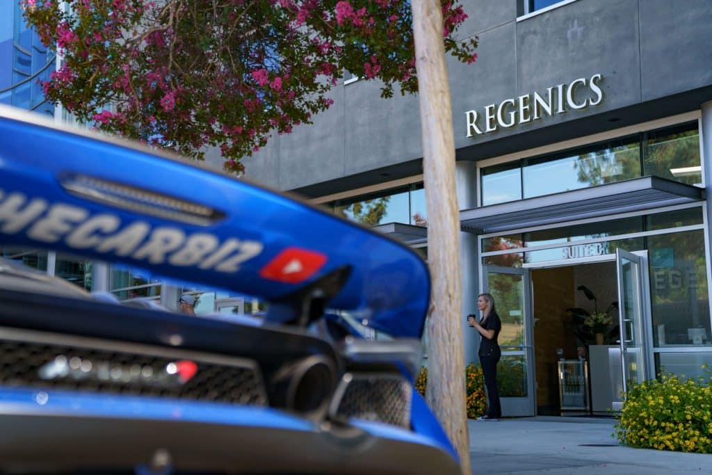 A blue car is parked in front of a building for a Test & Tune UP event.