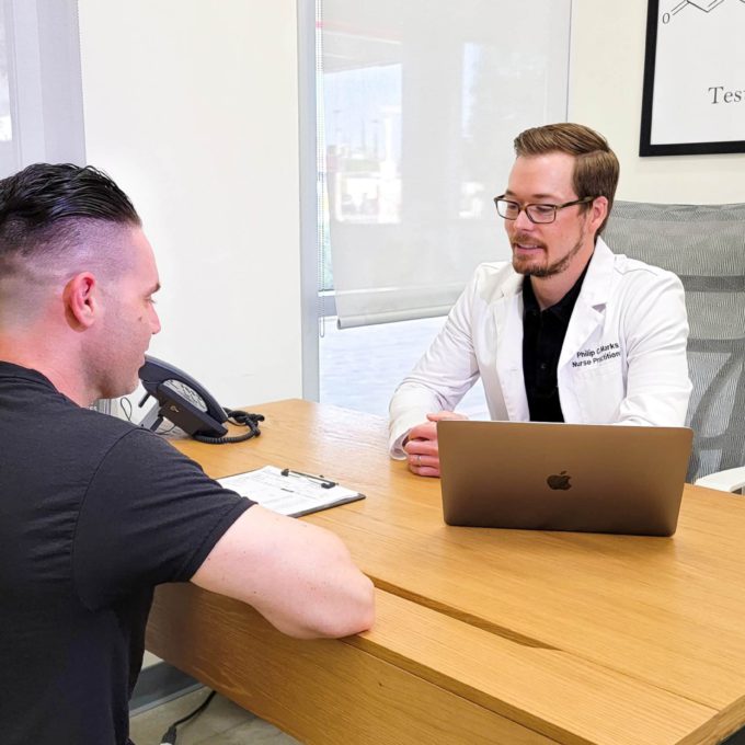 A doctor is talking to a patient at a desk about REGENICS.