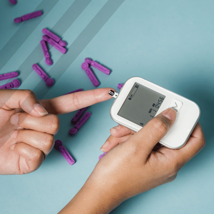 A woman's hand is holding a blood glucose monitor for regenics purposes.