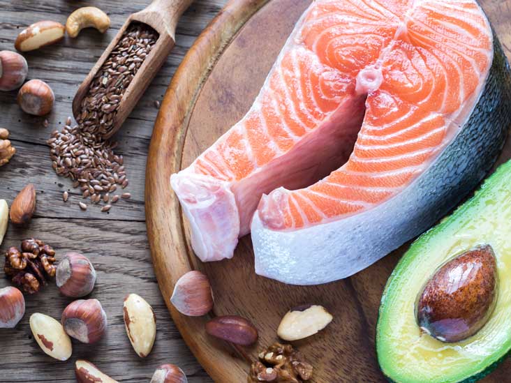 Discover the benefits of omega fatty acids by indulging in a delightful arrangement of salmon, avocado, and nuts on a wooden cutting board.