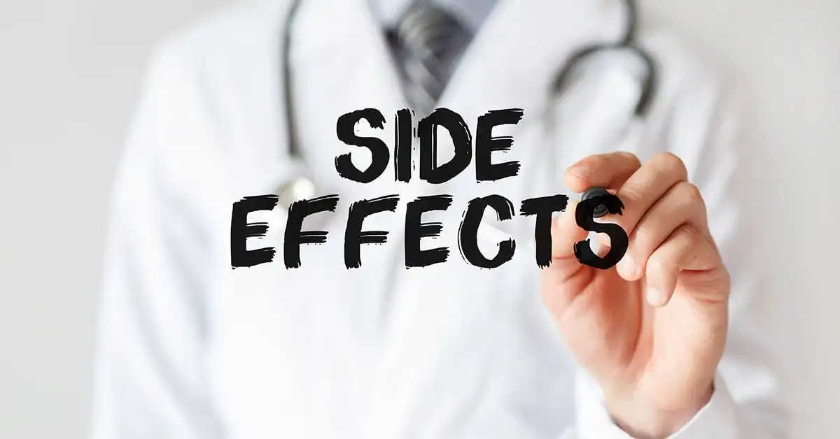 A doctor writing the word "side effects" on a piece of paper to discuss the potential risks associated with testosterone therapy.
