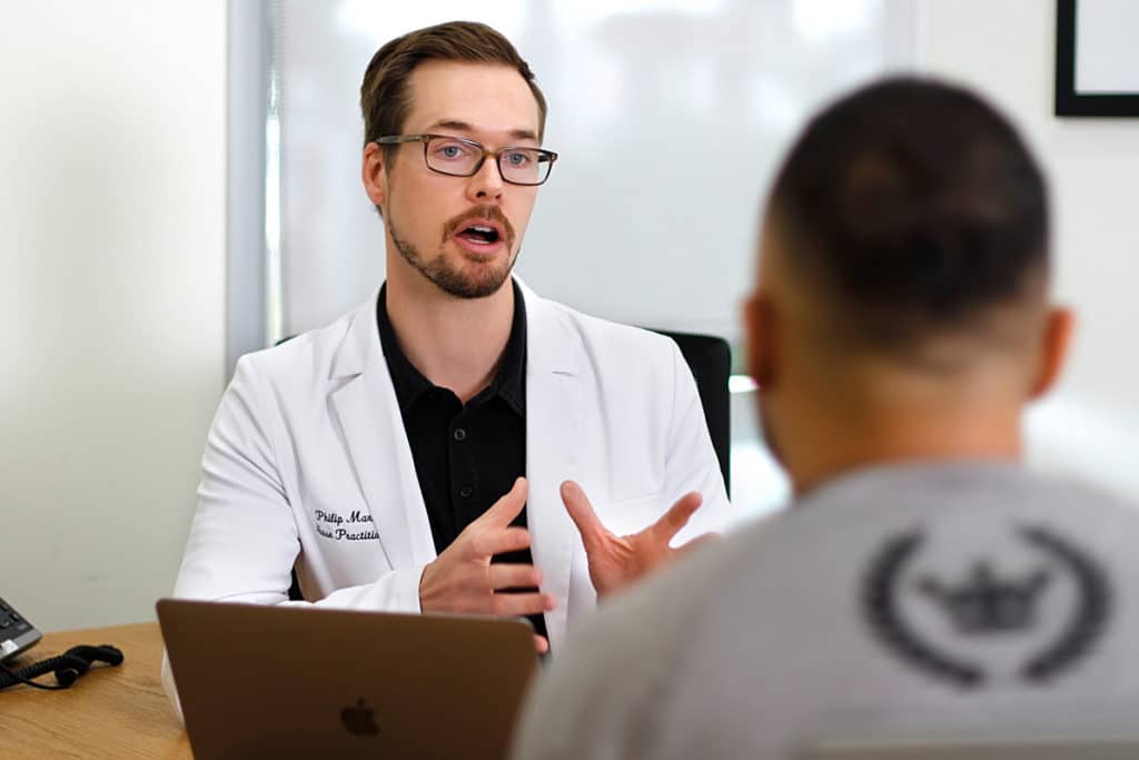 A doctor using REGENICS technology talks to a patient in front of a laptop.