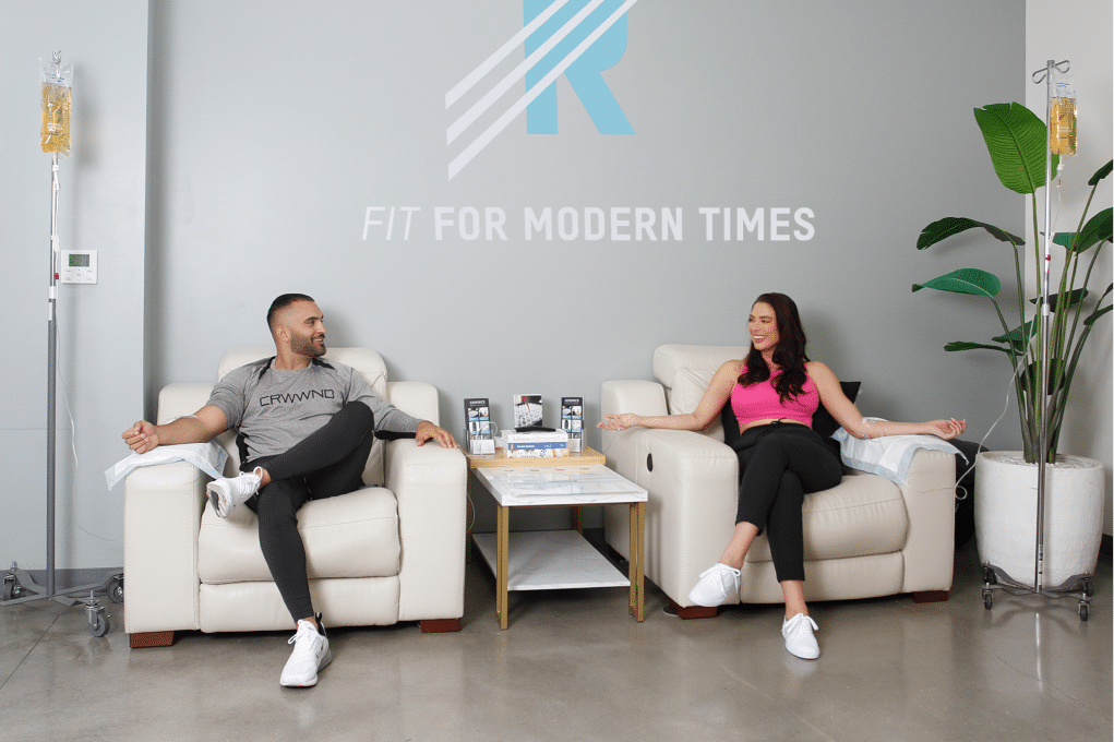 Two people sitting in chairs in a room with the word fit for modern times, receiving Beauty IV Infusions treatments.