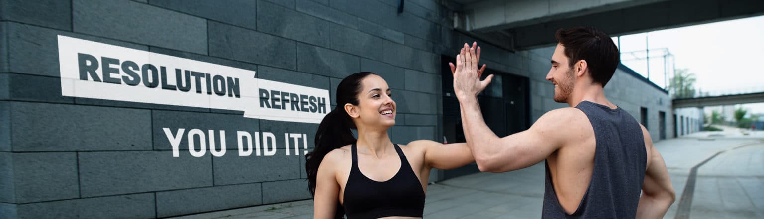 Two people giving a high five in front of a wall with New Year Resolution Refresh motivational phrases.