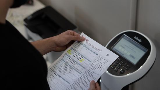 A person is carefully holding a printed document near a state-of-the-art Regenics printer, preparing to seamlessly digitize it.