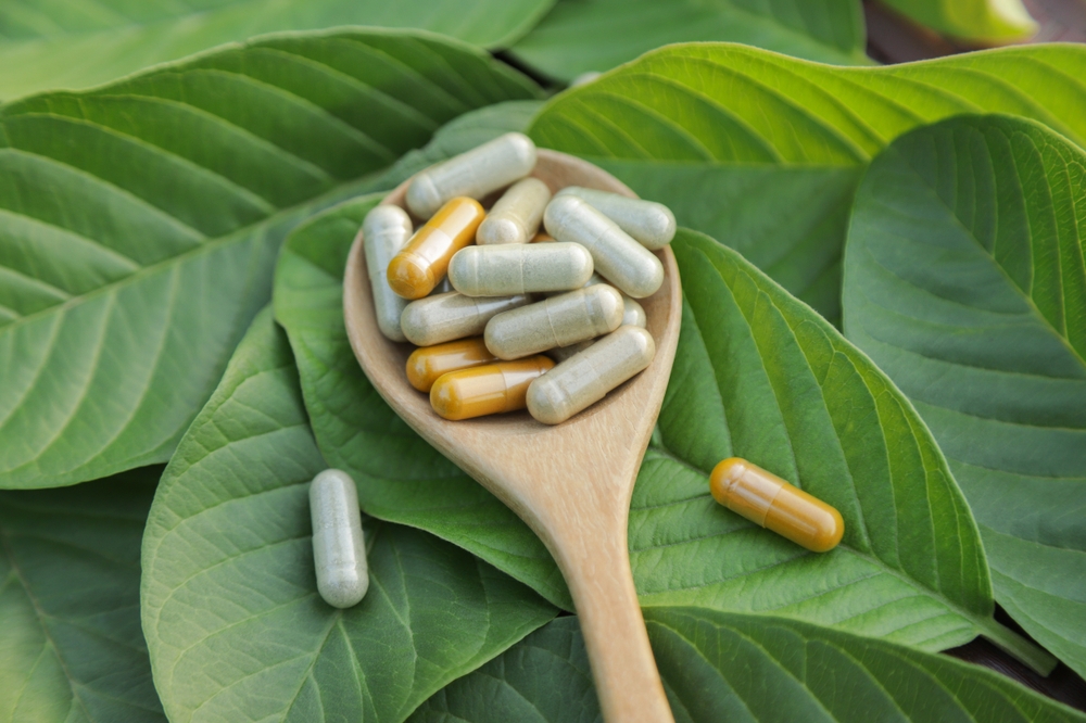 Herbal medicine in capsules from herb leaf on rustic wooden table