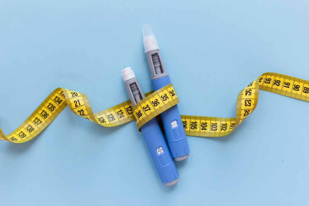 Two injectors dosing pens for subcutaneous injection of antidiabetic medication or anti-obesity medication hovering over a blue background