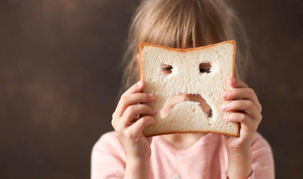 diet celiac. gluten intolerance. sad bread in the hands of a child. Gluten free concept