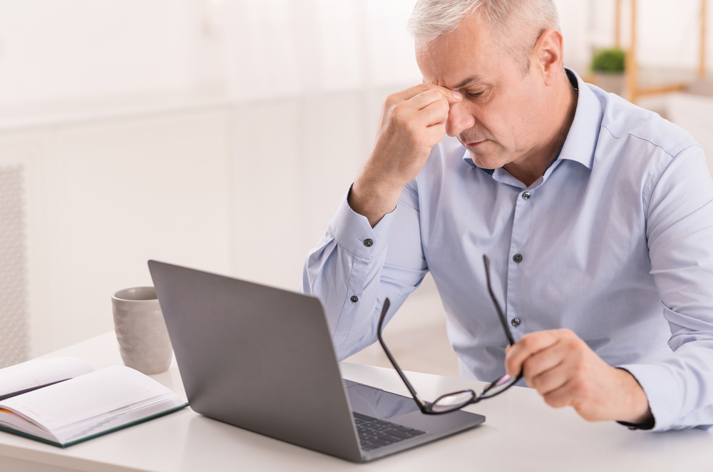 atigued senior businessman massaging nosebridge with closed eyes