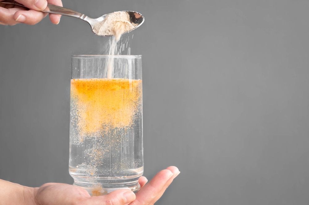 Orange fizzy electrolyte powder and water in a glass