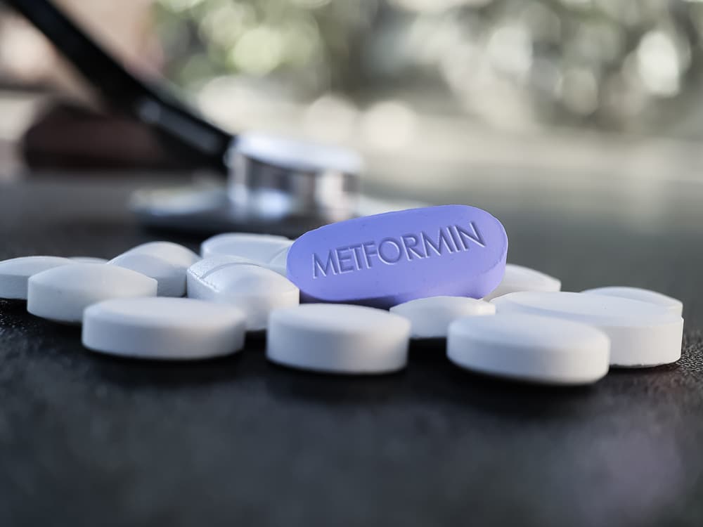 Blue Metformin Pill on Table with stethoscope and other tablets in background