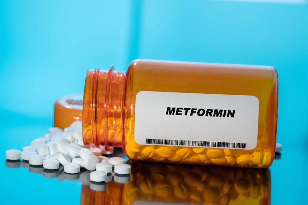 Metformin white medical pills and tablets spilling out of a drug bottle