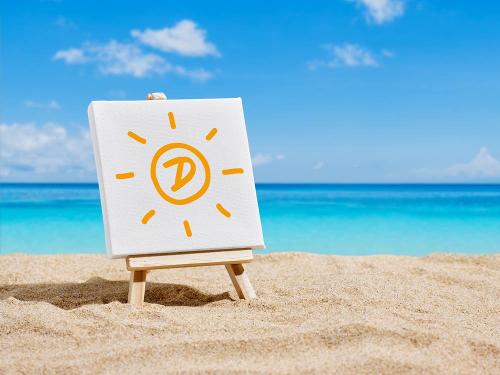 A canvas on an easel with sun and letter D symbols on the sands of a beach