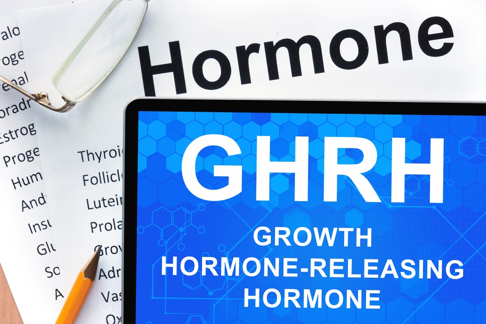 Papers with hormones list and tablet with words Growth hormone-releasing hormone