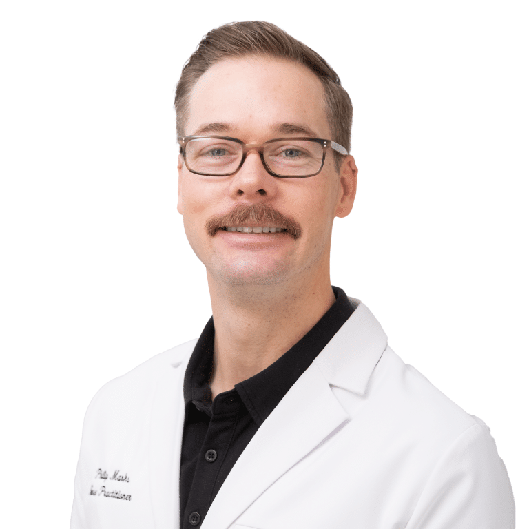 Man with glasses and a mustache wearing a white lab coat and black shirt, smiling, posed against a white background.